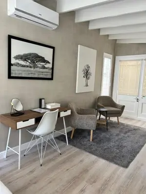 a living room with a desk and chairs and a table at One Oak Guest House in Somerset West