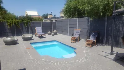 a swimming pool in a patio with chairs and a fence at Hayley's Place in Cape Town