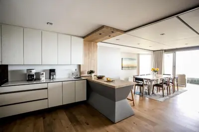 a kitchen with white cabinets and a dining room with a table at Bayview 203 in Hermanus