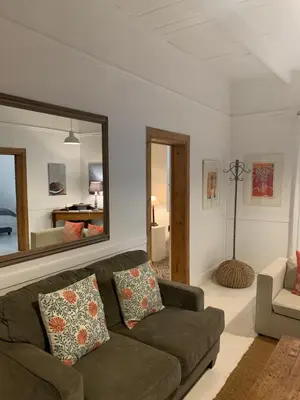 a living room with a couch and a mirror at The Missions House in Hermanus