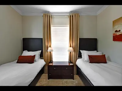 a bedroom with two beds and a table with two lamps at Sorbonne 1 - No loadshedding in Franschhoek