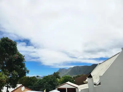 a white house with mountains in the background at Moondust near the ocean, food and wine in Hermanus