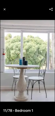 a table and two chairs in front of a window at Antilles on Beach in Cape Town