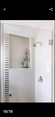 a shower with a glass door with a statue on a shelf at Antilles on Beach in Cape Town