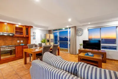 a living room with two couches and a table and a television at Ocean View 701 in Cape Town