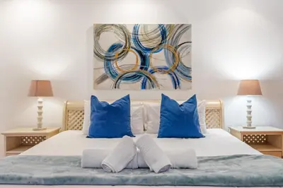 a bedroom with a bed with blue pillows and a painting at Ocean View 701 in Cape Town