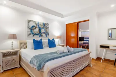 a bedroom with a large bed with blue pillows at Ocean View 701 in Cape Town