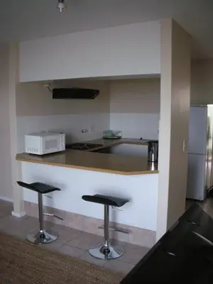 a kitchen with two bar stools and a counter at On The Beach Front Sea Spray in Bloubergstrand