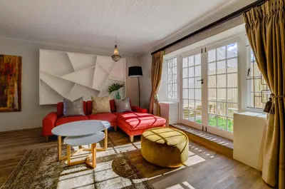 a living room with a red couch and a table at The Post House Hotel - no children under the age of 16yrs in Greyton