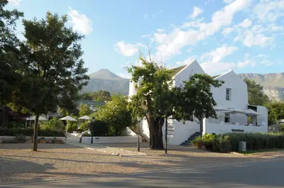 a white house with mountains in the background at The Post House Hotel - no children under the age of 16yrs in Greyton