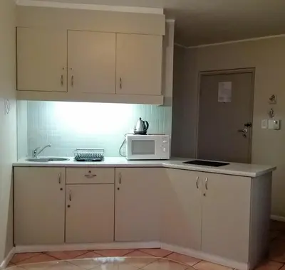 a kitchen with white cabinets and a microwave on a counter at OCEANPEARL 209 in Strand