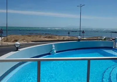 a blue swimming pool with the ocean in the background at OCEANPEARL 209 in Strand