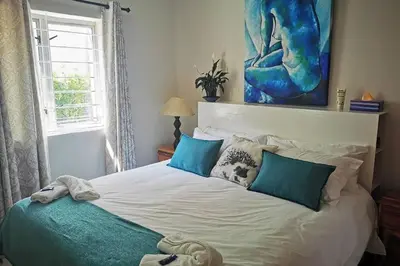 a bedroom with a large white bed with blue pillows at The Blue Horizon House - Botrivier in Caledon