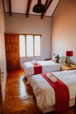 a bedroom with two beds with red blankets at Blue Crane Farm Lodge in Botrivier