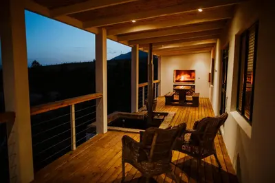 a screened in porch with two chairs and a fireplace at Blue Crane Farm Lodge in Botrivier
