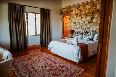 a bedroom with a large bed and a large wall at Blue Crane Farm Lodge in Botrivier