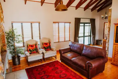 a living room with a leather couch and two chairs at Blue Crane Farm Lodge in Botrivier