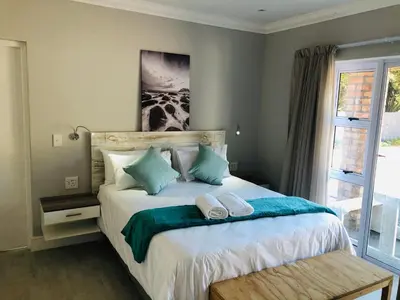 a bedroom with a bed with two pillows on it at Hermanus Guest Rooms in Hermanus