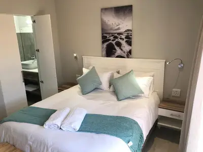 a bedroom with a white bed with blue pillows at Hermanus Guest Rooms in Hermanus