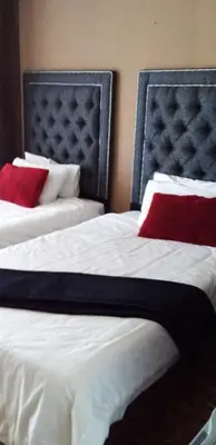 two beds with red pillows in a hotel room at Sir James Self Catering in Cape Town