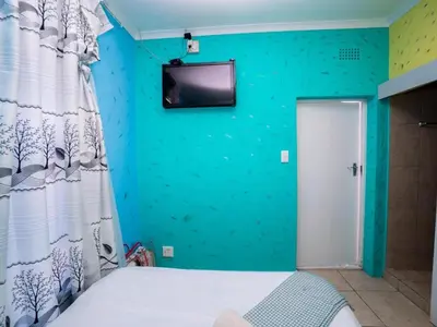 a bedroom with a blue wall with a tv on the wall at Relaxing Guest Huse in the heart of Ndabeni in Cape Town