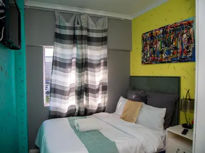 a bedroom with a bed and a painting on the wall at Relaxing Guest Huse in the heart of Ndabeni in Cape Town