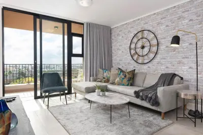 a living room with a couch and a brick wall at Waters Edge Apartments in Cape Town