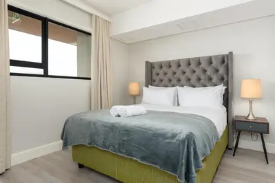 a bedroom with a large bed and a window at Waters Edge Apartments in Cape Town