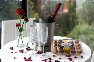 a table with a bottle of wine and a box of roses at 185 on BEACH Boutique Suites in Gordonʼs Bay