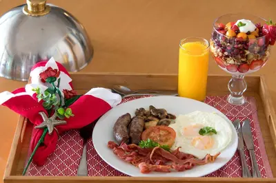a tray with a plate of breakfast food and a glass of orange juice at 185 on BEACH Boutique Suites in Gordonʼs Bay