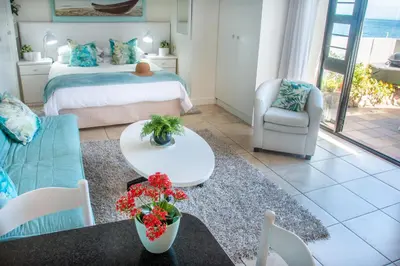 a living room with a bed and a couch and a table at 185 on BEACH Boutique Suites in Gordonʼs Bay