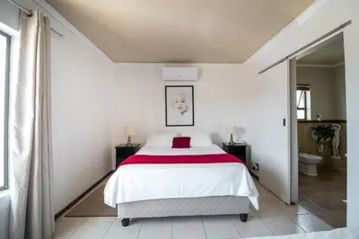 a bedroom with a bed with a red blanket at Broadway Tygervalley House in Cape Town