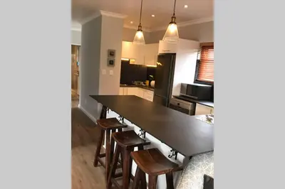 a kitchen with a large black table and wooden chairs at Winner in the Winelands in Franschhoek