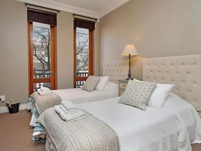 a bedroom with two beds and two windows at Church Street Luxury Apartments in Stellenbosch