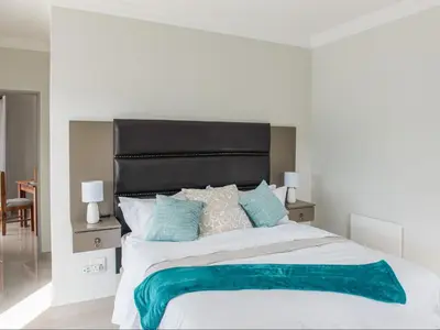 a bedroom with a large white bed with blue pillows at Elizabeth House in Hermanus