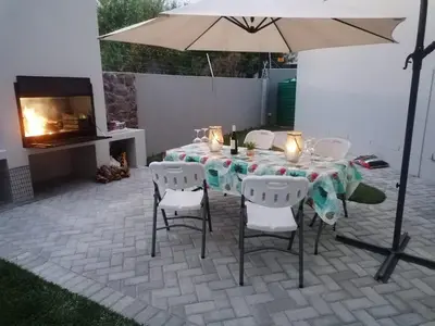 a table and chairs with an umbrella and a fireplace at Elizabeth House in Hermanus