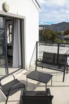 a balcony with two chairs and a table on it at Elizabeth House in Hermanus
