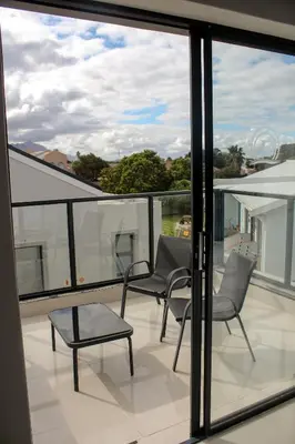 a balcony with two chairs and a table and windows at Elizabeth House in Hermanus