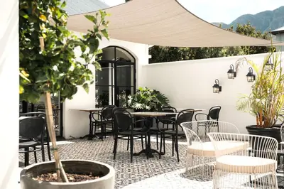 an outdoor patio with tables and chairs and plants at Franschhoek Maison du Cap in Franschhoek