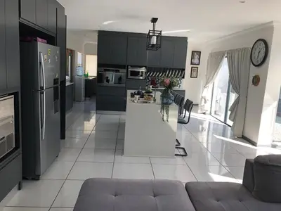 a kitchen with black cabinets and a white floor at Spoelklippies in Hermanus