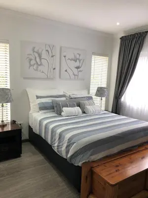 a bedroom with a large bed with blue and white sheets at Spoelklippies in Hermanus