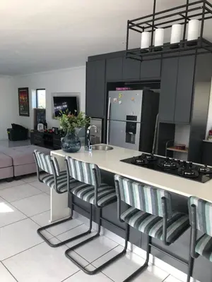 a kitchen with a counter with chairs and a sink at Spoelklippies in Hermanus