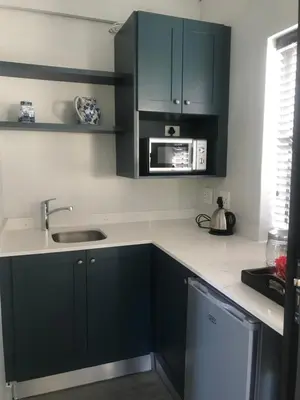 a kitchen with green cabinets and a sink and a microwave at Comfortable Room with Large en suite Bathroom in Franschhoek