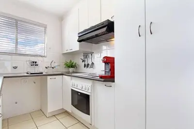 a kitchen with white cabinets and a red appliance at Hermanus Beach Club - 106 - Apartment with a view in Hermanus