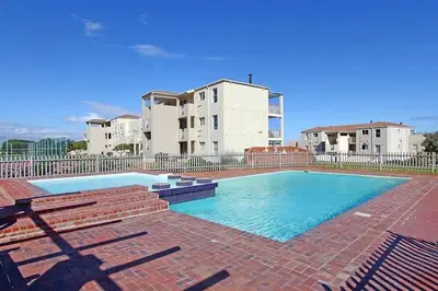 a large swimming pool in front of a building at Hermanus Beach Club - 106 - Apartment with a view in Hermanus