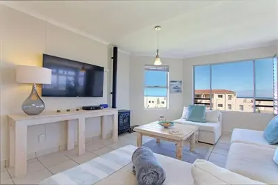a living room with a couch and a tv at Hermanus Beach Club - 106 - Apartment with a view in Hermanus