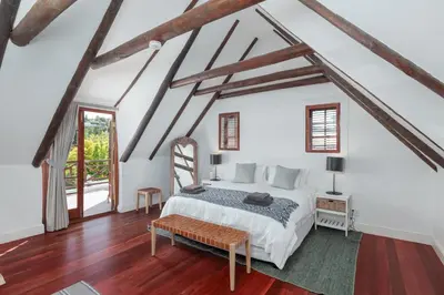 a bedroom with a white bed and wooden floors at Die Rietdak - Reetdachhaus mit vier Schlafzimmern in Cape Town