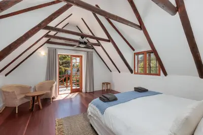 a bedroom with a bed and a table and chairs at Die Rietdak - Reetdachhaus mit vier Schlafzimmern in Cape Town