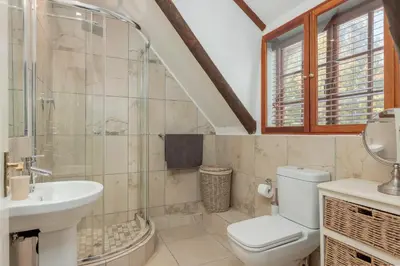 a bathroom with a toilet and a sink at Die Rietdak - Reetdachhaus mit vier Schlafzimmern in Cape Town
