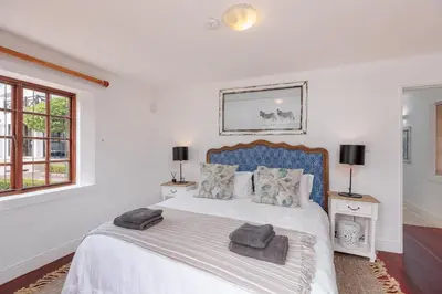 a white bedroom with a large bed with pillows at Die Rietdak - Reetdachhaus mit vier Schlafzimmern in Cape Town